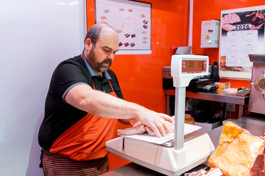 Butcher weighing fresh meat on digital scale in shop