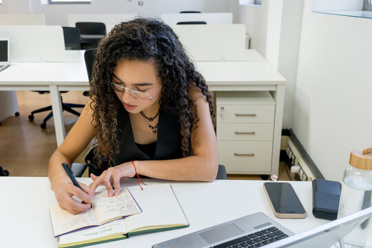 MBA student take notes at desk in modern office