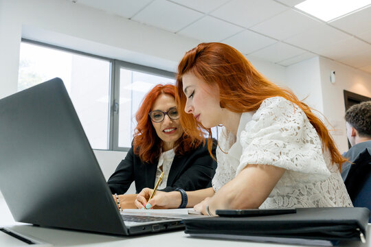 MBA students collaborate on laptop assignment in classroom