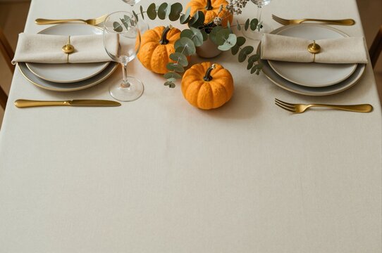 elegant thanksgiving table setting with mini pumpkins and gold cutlery for autumn celebration