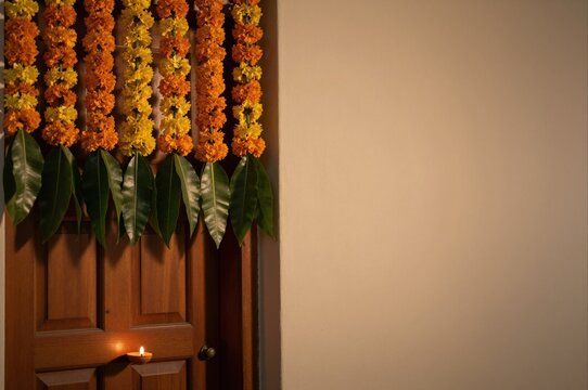 traditional indian marigold flower garland hanging on wooden door for festive decoration