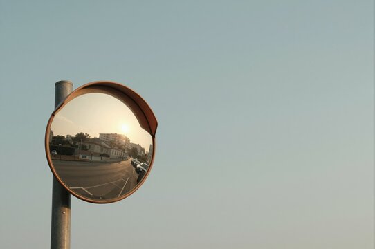 sunset landscape reflection in convex mirror on urban street under clear blue sky