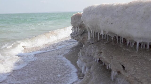 Cream ice, ice fat on Azov Sea. In calm, frosty weather, even salt water freezes, pancake ice forms, The waves knock the ice into white frozen stripes on the shore, the white foam and sand hardens