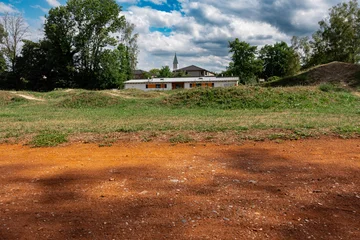Mini bike pump track in Emmering near Fuerstenfeldbruck, Bavaria, outdoor dirt cycling circuit with clubhouse building and village church tower in green small town landscape © Natalia Schuchardt