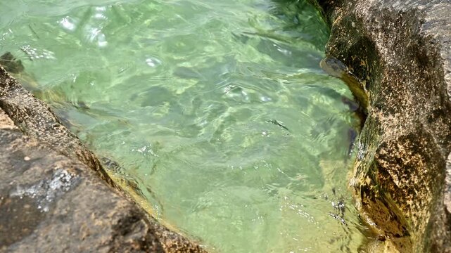 Clear turquoise water flows over rocky shoreline in natural coastal setting
