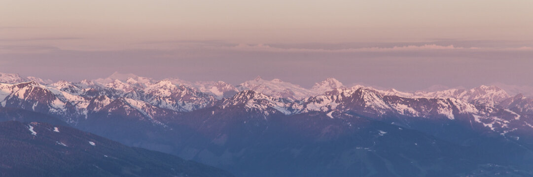 View of the snow-capped peaks of the Dachstein glacier at sunset with soft pink light illuminating the rugged alpine landscape in Liezen District, Styria, Austria.