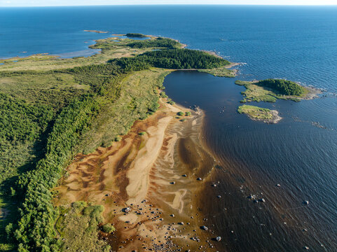 Aerial view of a scenic rocky cape on Lake Ladoga with low water level and sand textures on the dried beach, Karelia, Russia