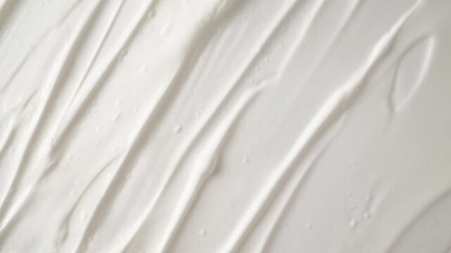Smooth white cosmetic cream texture scrolling up top view. White face body cream texture moving smoothly. Perfect for skincare and beauty industry advertising.
