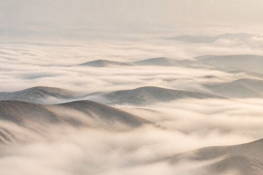 Layers of rolling hills emerge from a thick blanket of low-lying fog or clouds.