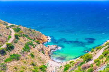 Obraz premium Aerial view of Cala Tio Ximo cove beach Benidorm bay Mediterranean Sea azure turquoise water, Costa Blanca coastline coast, road in Serra Gelada natural park in summer day, Valencian Community, Spain
