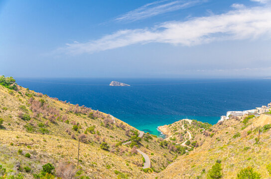 Aerial panoramic view of Benidorm bay Mediterranean Sea azure water with Isla de Benidorm island, Costa Blanca coastline, Tio Ximo Cove Cala in Serra Gelada natural park in summer day, Spain