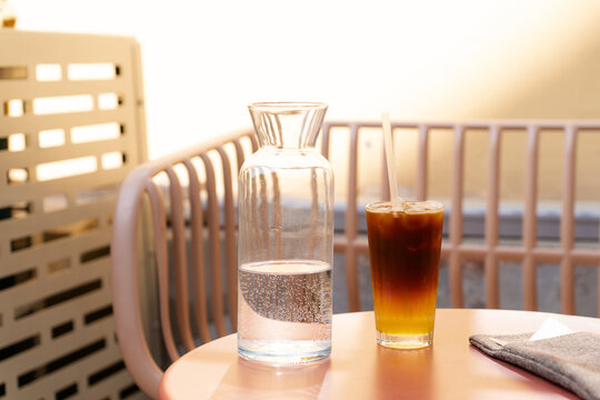 Iced bumble coffee and a water pitcher on an outdoor cafe table