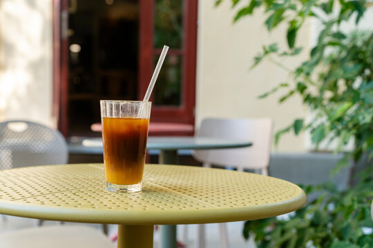 Iced bumble coffee and a water pitcher on an outdoor cafe table