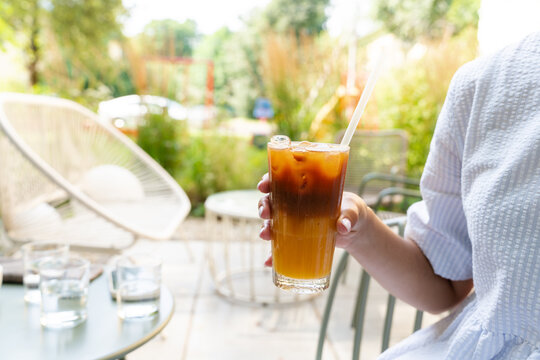 Woman hand holding layered iced bumble coffee outdoors