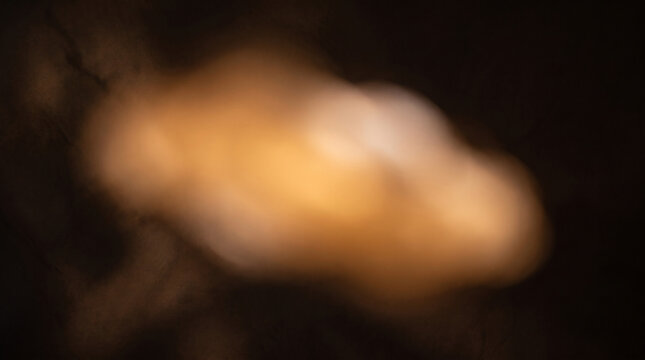 Warm golden bokeh light leak on black background, soft amber glow with cinematic blur, abstract orange light flare for overlay and compositing