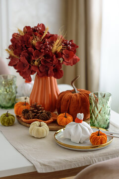 Autumnal table setting with pumpkins and flowers for Thanksgiving celebration