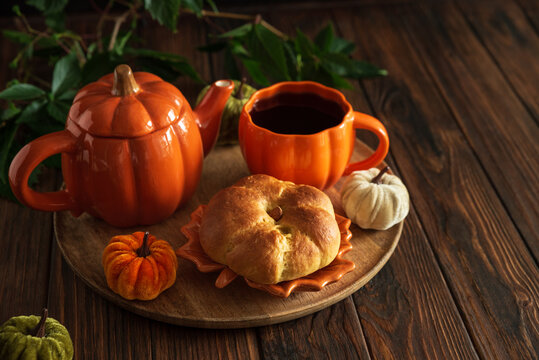 Cozy Autumn Scene with Pumpkin Teapot Coffee Cup and Pastry on Wooden Table