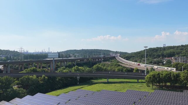 Drone gliding over solar panels with an elevated highway beyond