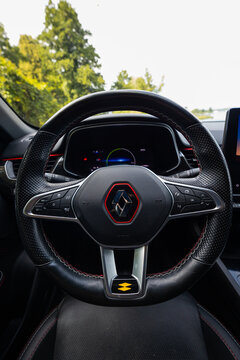 Close up of Renault Arkana RS Line steering wheel shows red stitched leather, perforated grips, RS accent ring, Renault emblem, digital cluster, buttons, and paddles.