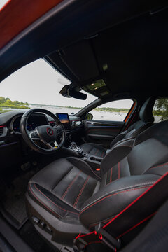 Cockpit view shows RS Line badges, red stitched leather, flat bottom wheel, portrait touchscreen, bucket seats, aluminum pedals, red seatbelt, and panoramic roof.