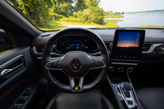 Interior view shows RS Line wheel with red stitching, digital cluster with driver assist, portrait infotainment, metallic toggles, rotary vents, and E Tech gear selector by a lakefront drive.