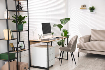 Fototapeta premium Cozy workplace with wooden desk, computer and stylish furniture in office. Interior design