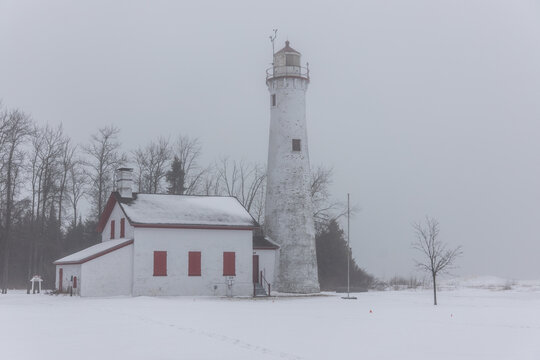 Aerial view of Sturgeon Point Lighthouse surrounded by snow and fog in Harrisville, Michigan, United States.