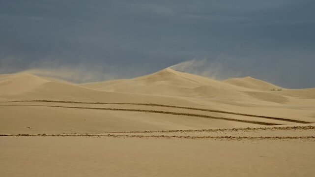 Desert landscape with rolling sand dunes and dramatic cloudy sky