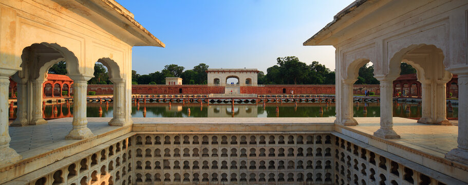 View of the historic Shalamar Gardens featuring ornate marble pavilions and a serene reflecting pool surrounded by red sandstone walls in Lahore, Punjab, Pakistan.