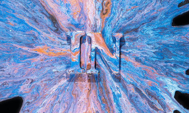 Liquid paint pour forming glossy letters IN with radial marbled blue and orange flow