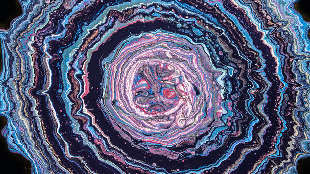 Concentric fluid paint rings in pink blue and purple resembling geode cross section
