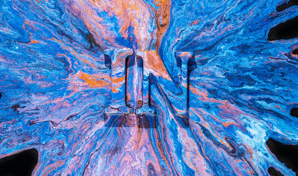 Blue orange marbled paint pour with raised letter N centered on vibrant swirling abstract surface
