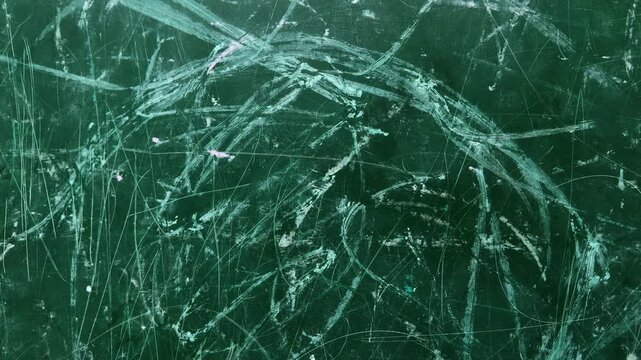 green classroom chalkboard as the camera slowly pushes in, revealing layers of chalk marks, erased drawings, scratches, and handwritten traces. The textured surface reflects years of learning