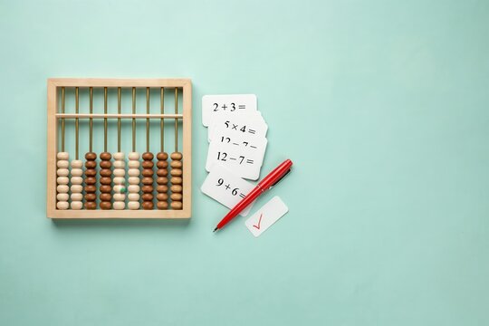 Educational setup featuring wooden abacus, math cards, and red pen for arithmetic practice
