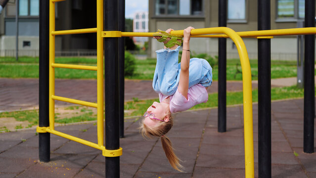 Happy child having fun upside down on the playground monkey bars