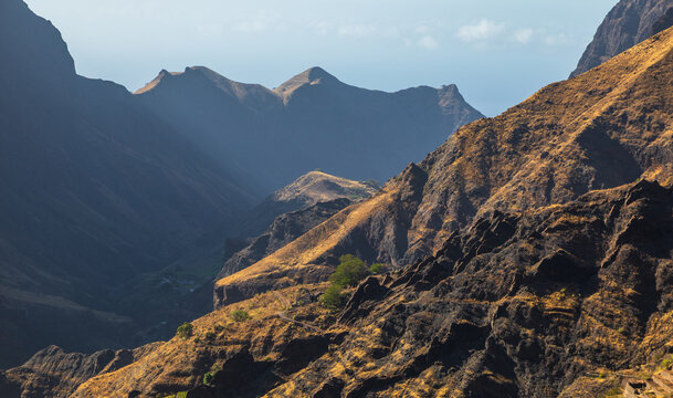 View of the rugged volcanic mountain landscape of Santo Antao with deep valleys and sunlit slopes in Alto Mira, Porto Novo, Cabo Verde.