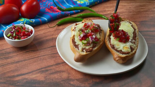 Melted Cheese Molletes with Refried Beans and topping with fresh pico de gallo