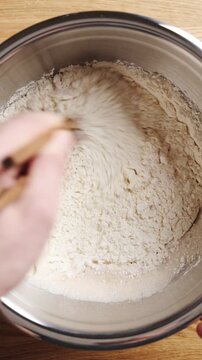 Chopsticks mix ingredients for soft bao dough. Bao dough combines wheat flour, yeast, sugar, water and oil. Bao dough is base for Asian street food, restaurant menu, homemade snacks or dinner.