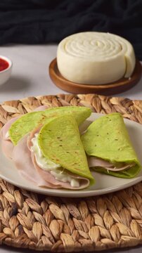 Green nopal tortillas quesadillas with red spicy salsa and fresh Oaxacan cheese on table