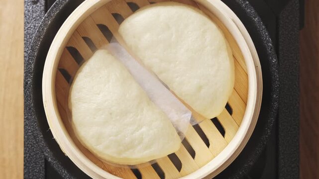 
Steamed bao buns sit in bamboo steamer. Bao buns can be filled with pork, chicken, beef, tofu, vegetables or mushrooms. Bao buns make popular Asian street food, snack, lunch or homemade meal.