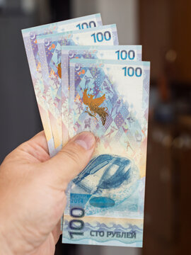 Hand Holding Russian 100 Ruble Banknotes with Colorful Design