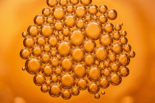 Densely packed cluster of bright orange liquid bubbles creating a vibrant abstract geometric pattern
