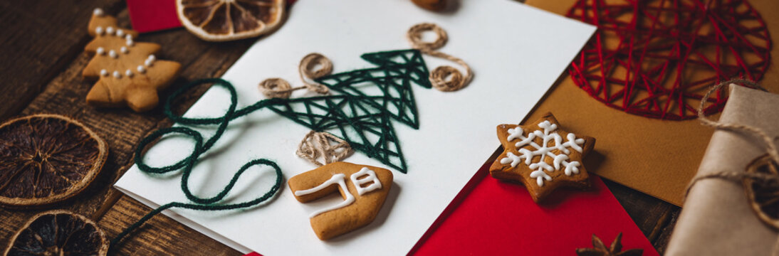 Banner. Traditional Christmas handmade crafted postcard, gingerbread cookies. Wooden background. Festive mood, cozy home atmosphere. Family time, holiday leisure. Natural materials, zero waste