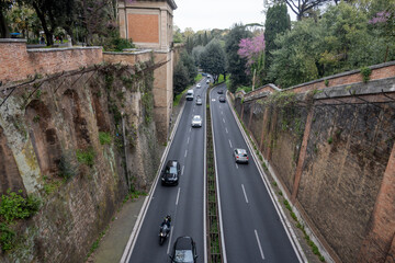Ancient Roman road Via in Rome historic sunken road with preserved ancient stone walls flanked by modern traffic, travel photography, architectural themes, driving in Rome © barmalini