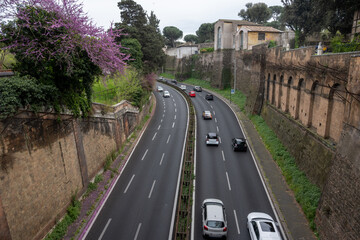 Ancient Roman road Via in Rome historic sunken road with preserved ancient stone walls flanked by modern traffic, travel photography, architectural themes, driving in Rome © barmalini