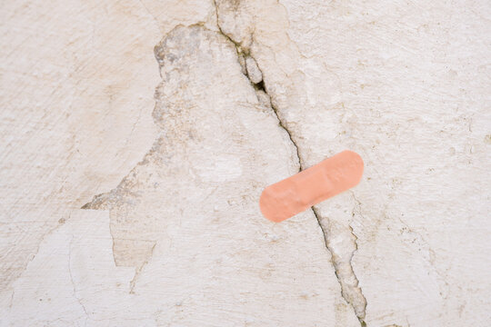 A band-aid placed on a crack in a wall shows an attempt to cover damage in a room
