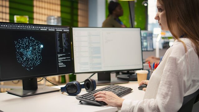 Close up of an IT expert coding with AI language model assistance in a startup office, typing on a computer keyboard and integrating LLM suggestions into a code editor for software development.