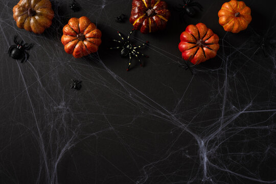 Happy Halloween display with pumpkins, spider decorations and spooky cobwebs on black background