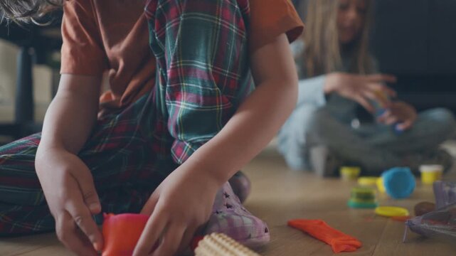 Boy squishing a clay ball surrounded by craft cutters and rolling pins