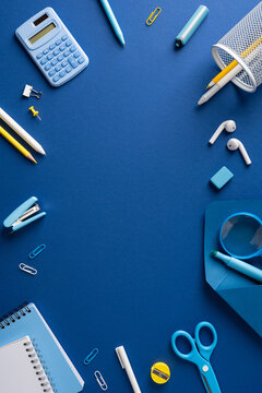 Back to school blue stationery vertical flat lay with notebook, pencils, calculator and organized workspace